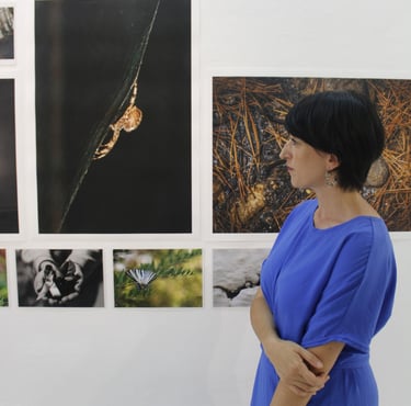 Asimina Georgakopoulou facing photographs during an exhibition by the Eyes of Light Organization
