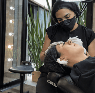 Esteticista profesional realizando microblading de cejas en un salón de belleza.