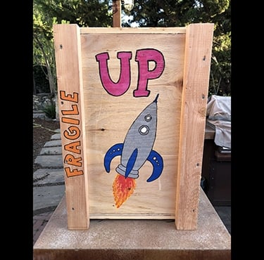 Shipping crate for Talbotics sculpture with image of rocketship drawn on it.