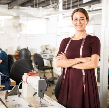 Una diseñadora de moda sonriente, de pie en una fábrica de confección