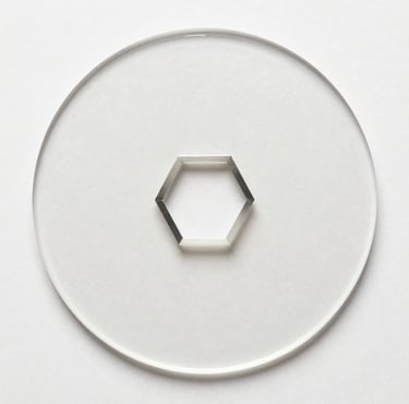 A silver hexagonal nut centered on a clear circular glass plate with a white background.