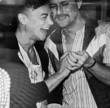 black & white image of friends laughing heartily and holding each other