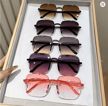 Collection of rimless oversized square sunglasses with gradient tinted lenses in a display tray.