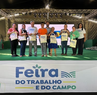 pessoas alinhadas em um palco com cada uma segurando uma sacola estampada com “Feira do trabalho"