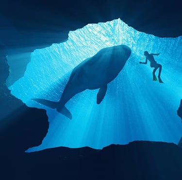 A scuba diver and a large whale silhouette swimming in a deep blue underwater cave with sunlight rays.