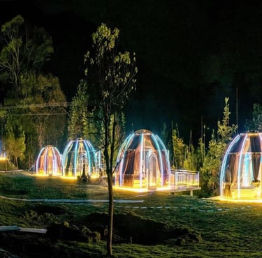 غرف زجاجية مضيئة على شكل فقاعات شفافة تحتوي على جلسات طعام خاصة بإطلالة على البحيرة