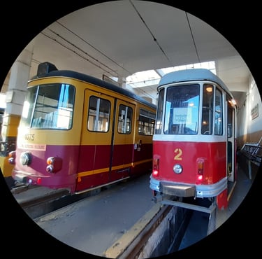 Para zabytkowych tramwajów, żółtoczerwony i białoczerwony, obok siebie, w muzeum.