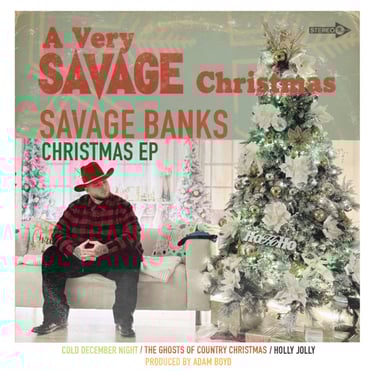 Savage Banks sitting on a beige couch with a red cowboy hat and red flannel on, next to a Christmas tree with festive decor.