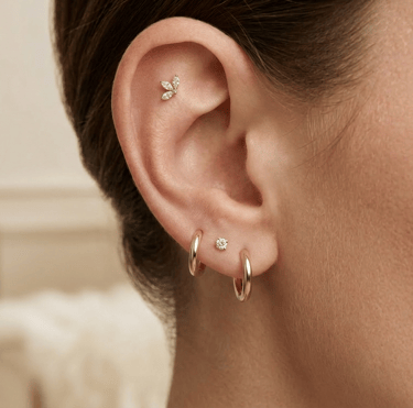 אוזן עם שילוב עגילי חישוק מזהב ופירסינג פלאט הליקס