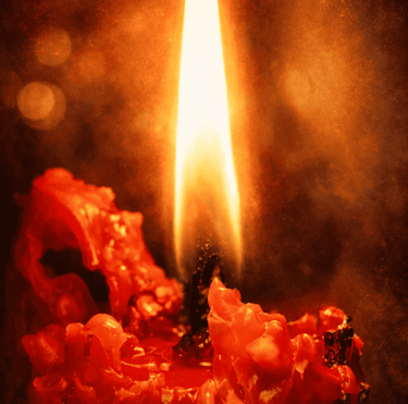 Una sola llama de vela roja encendida, con cera derritiéndose y un fondo de bokeh luminoso.