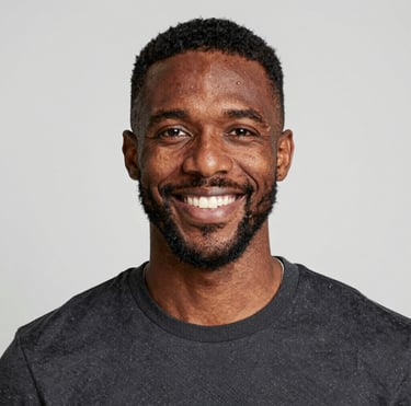 A smiling woman with curly hair enjoying a sunny outdoor cafe.