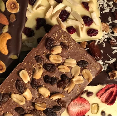 Handcrafted gourmet chocolate bars topped with dried fruits and nuts, elegantly arranged for gifting or indulgence.