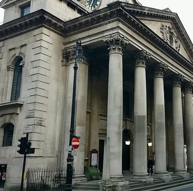 numerous columns  large church building with large door and an old clock in the middle 