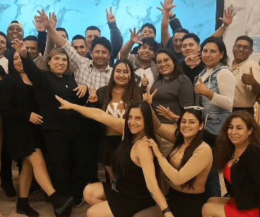 A diverse group of cheerful colleagues cheering and posing together at a corporate team building event.