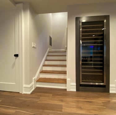 Finished basement featuring staircase with wine cooler installed under the stairs