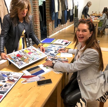 Brooke Shields sitting at a table working with Christina Treviño