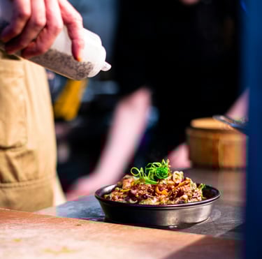 pouring sauce over an ovendish made by a chef