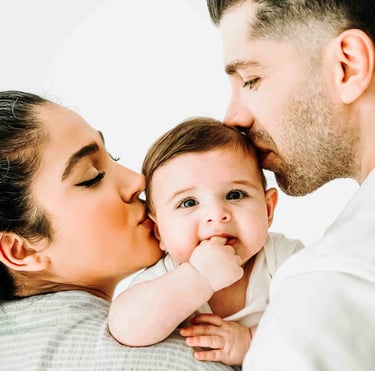 Parents kissing baby during family photoshoot – Fred Art Studio session