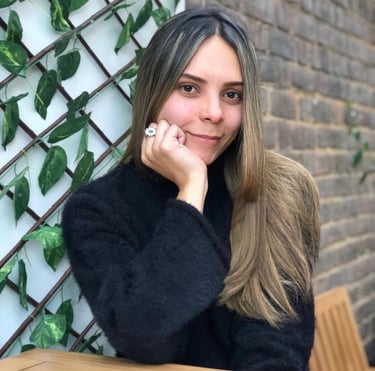 una mujer sonriendo a la camara sutilmente con su mano sosteniendo su cara