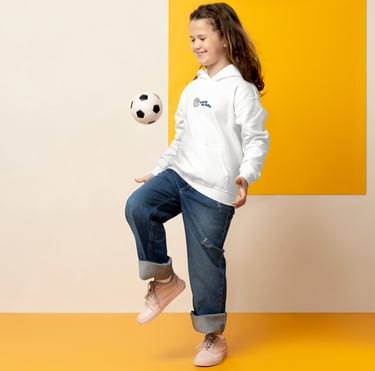 Young girl in a white hoodie and jeans balancing a soccer ball on her knee.