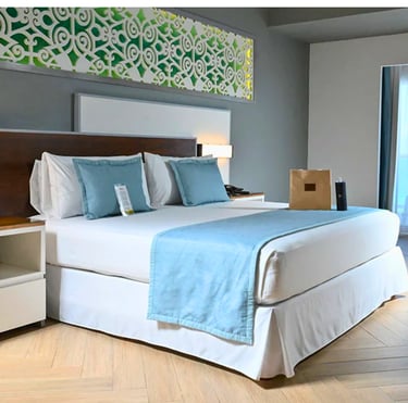 Modern luxury hotel room featuring a king bed with light blue accents and a decorative wall headboard.