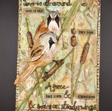 Hand‑sculpted clay artwork depicting two bearded tits among cattails with textured details..
