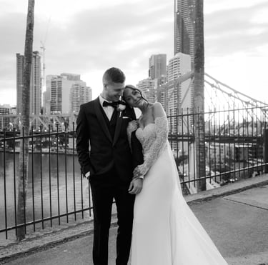 a bride and groom kissing in front of a bridge