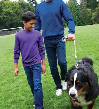 a man and a boy walking a dog on a leash