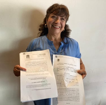 Smiling woman holding official divorce decree papers from a court in Tecate, Baja California.