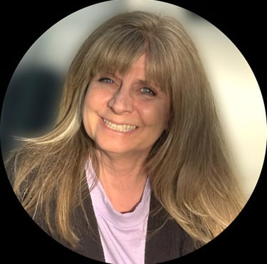 Headshot of a smiling woman with long blonde hair and bangs wearing a purple shirt.