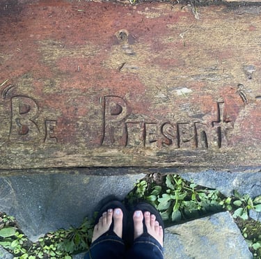 words "Be present" carved into wood
