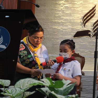Little kids scout speaking on a podium while reading off a paper