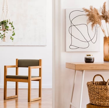 Doorkijkje in kamer met vierkante houten stoel in het midden, een sterachtige plant linksvoor.