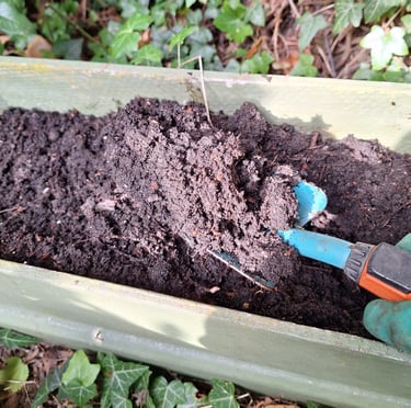 a person that is fertilizing garden bed soil