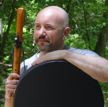 Incredibly handsome bald guy holding a flute and drum.