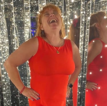 Picture of Teva in a red cocktail dress on Resilient Lady, Virgin Voyages cruise, enjoying a laugh 