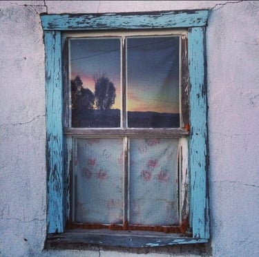 ventana azul con atardecer en el reflejo