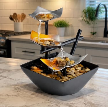 A modern 3-tier tabletop water fountain with glowing river rocks on a kitchen counter.