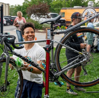 Smiling young man washing a bike with a sponge