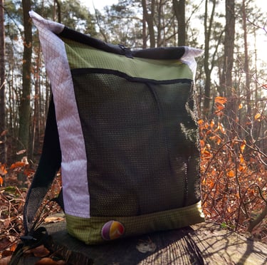 An ultralight backpack lying on the trunk, forest in the backgrond.