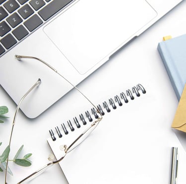 Image of a notebook with a laptop, glasses and eucalyptus leaves