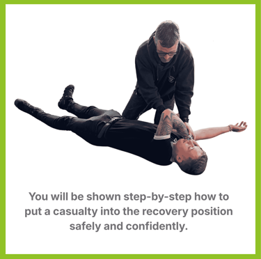A man places another man in the recovery position after an emergency.