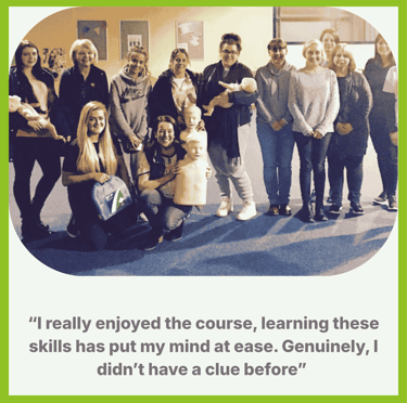 A group of learners at the end of their training session smiling and holding the training manikins 