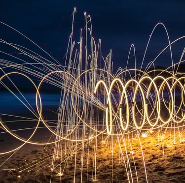 Spiraling fire lights at night on a sandy beach