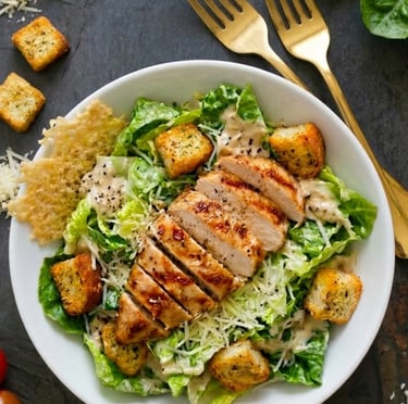Fresh grilled chicken Caesar salad with romaine lettuce, croutons, and parmesan cheese in a white bowl.