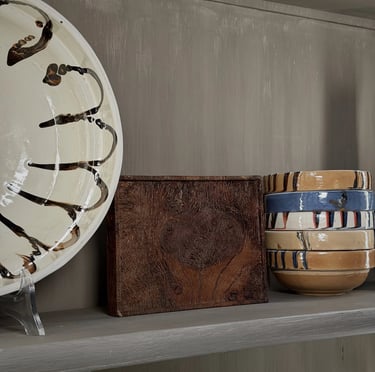 Two lit tea light candles resting in smooth, pebble-shaped wooden holders on a dark surface.