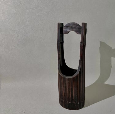 Handcrafted dark brown bamboo flower vase with a traditional Japanese hanging handle design.