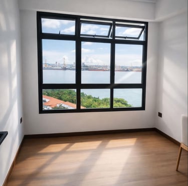 Empty modern room with wood flooring and a large black window overlooking a scenic harbor and blue ocean.