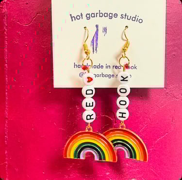 Gold huggie-hoop dangle earrings with beads that spell “red hook” and rainbow charms
