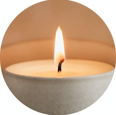 Circular image showing a lit candle in a gray ceramic vessel with a soft flame.